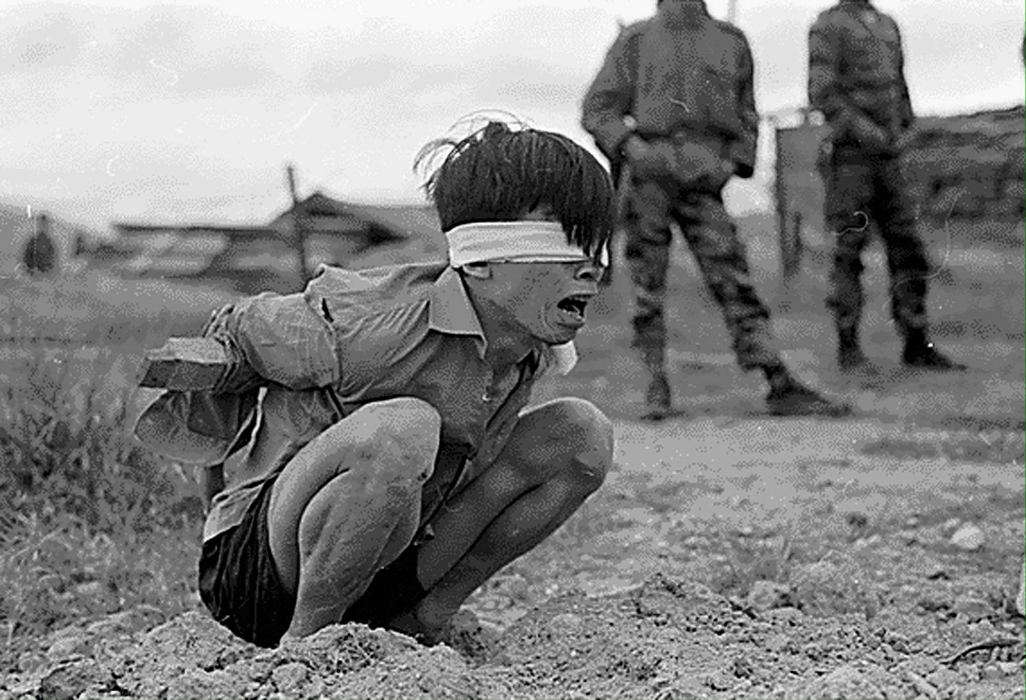 Foto van een Vietnamees jongetje als oorlogsgevangen die vastgehouden word